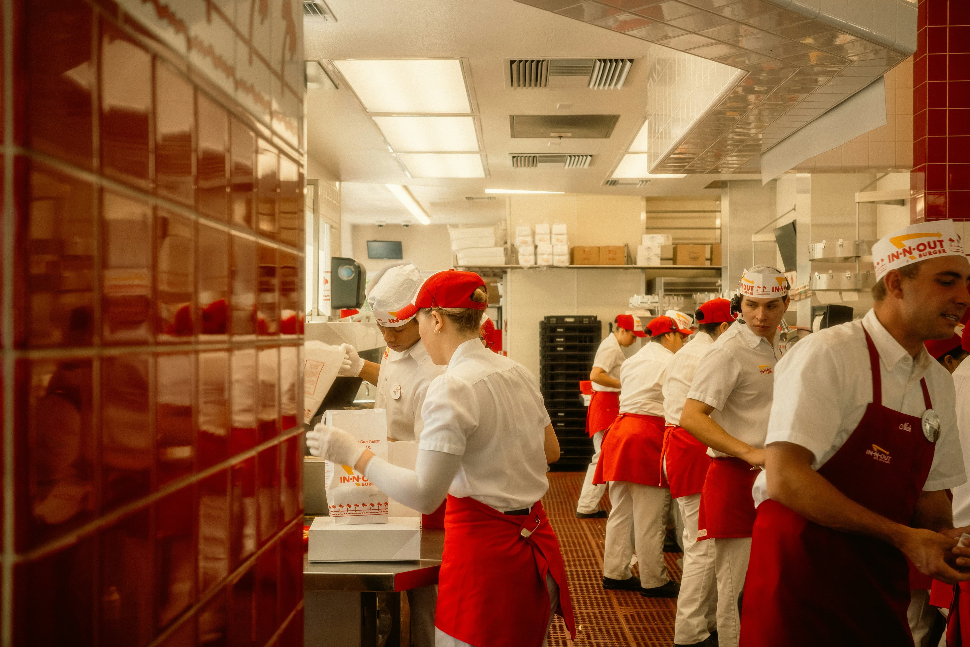 Restaurant kitchen staff in red aprons working a busy service